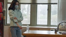 Corona pandemic Girl with face mask using hand sanitizer to prevent coronavirus