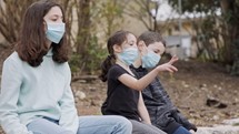 Coronavirus pandemic - kids wearing face masks to avoid contagion sitting bored