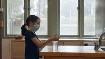 Corona pandemic Girl with face mask using hand sanitizer to prevent coronavirus