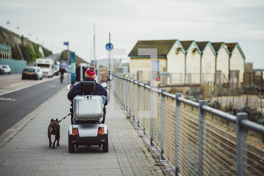 man in a power chair walking his dog 