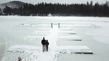 people walking on a dock over a frozen lake 