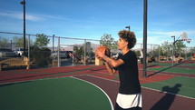 a young man playing basketball outdoors 