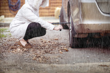 a woman changing a tire in the rain 