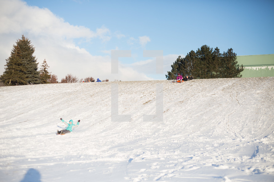kids sledding down a hill 