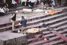 dead bodies wrapped in a blanket on temple steps 