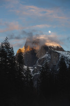 Moon over snowy mountain and trees in Yosemite