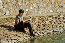 Man reading the Bible by a lake.