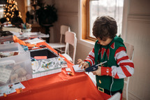 a little boy in an elf costume making crafts 