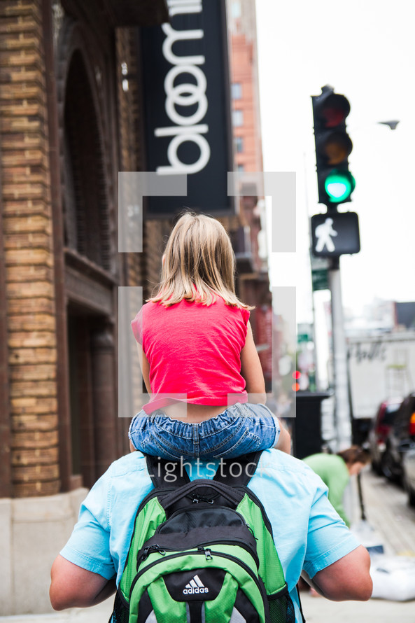 daughter on father's shoulders walking on a sidewalk in Chicago 