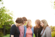 women standing in a backyard praying together 