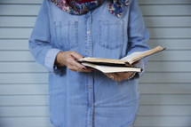 an elderly woman standing reading a Bible 