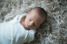 a swaddled newborn baby sleeping 