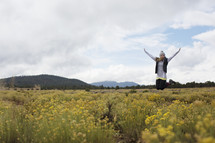 A young woman jumps in the air in a field of flowers.