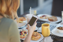 a woman checking her cellphone over breakfast 