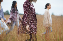 women walking through a field of tall grasses 