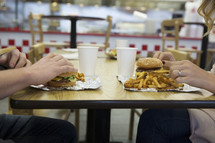 couple sitting across from one another eating fast food 
