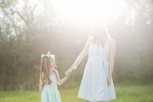 a mother and daughter outdoors holding hands