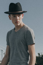 a young man posing in a hat 