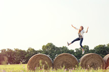 woman running and jumping on hay bales 