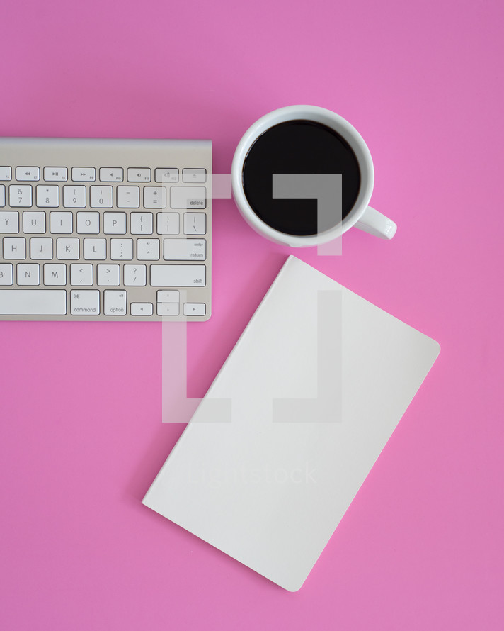 coffee mug, notebook, computer keyboard on a desk 