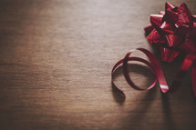 a shiny red bow and ribbon on wood