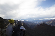friends sitting on a mountaintop looking out 