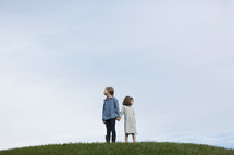 sisters standing on a hilltop holding hands