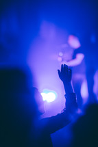 a teen with raised hands at a concert 