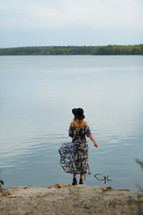 woman in a dress standing on a shore  