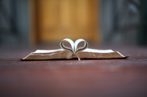 pages of a Bible folded into the shape of a heart in a doorway