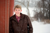 teen boy standing in falling snow 