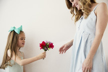 a little girl giving her mom flowers.