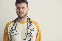 man with a string of Christmas lights around his neck 