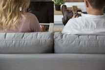 a woman sitting next to a man on a couch while typing on a laptop computer 