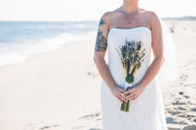 a bride on a beach holding a bouquet 