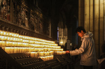 a man lighting a prayer candle in a cathedral 