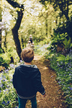 a boy walking on a path in the woods 