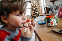 a kid sitting at a table with hot cocoa and eating at Christmas 