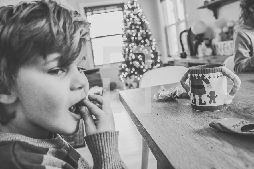 a kid with hot cocoa eating at the table at Christmas 