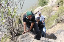 men climbing up a rocky terrain 