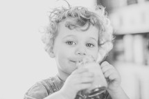 a little boy drinking from a glass 