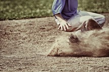 A young boy sliding into a base in a baseball game