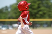 A boy runs for home plate in a little league baseball game