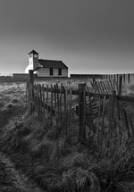 fence line and a white church on a beach