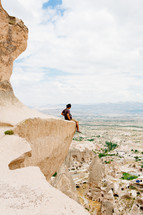 a man sitting at the edge of a cliff 