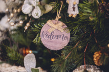 Wooden ornament with the word "redeemer" on a Christmas tree 