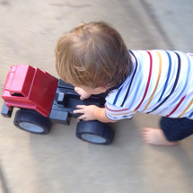 a toddler boy pushing a toy truck 