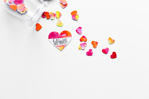 Top view of watercolor hearts scattered on white background with one labeled FORGIVEN. 