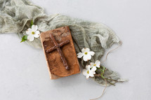 wooden cross on an old Bible and dogwood flowers 