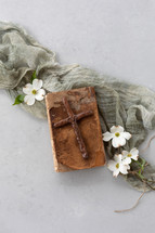 wooden cross and dogwood flowers on an old Bible 